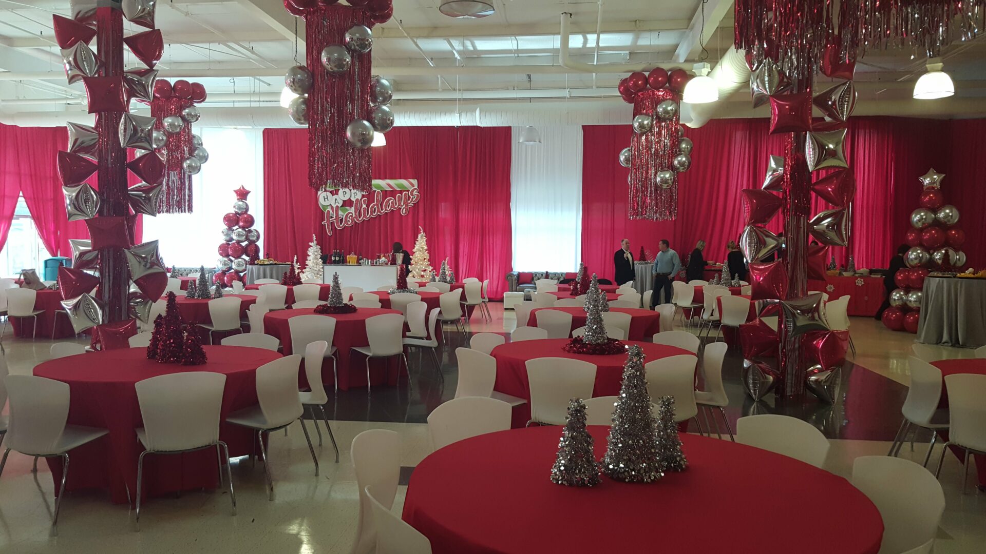A room with red and white tables, chairs, and balloons.