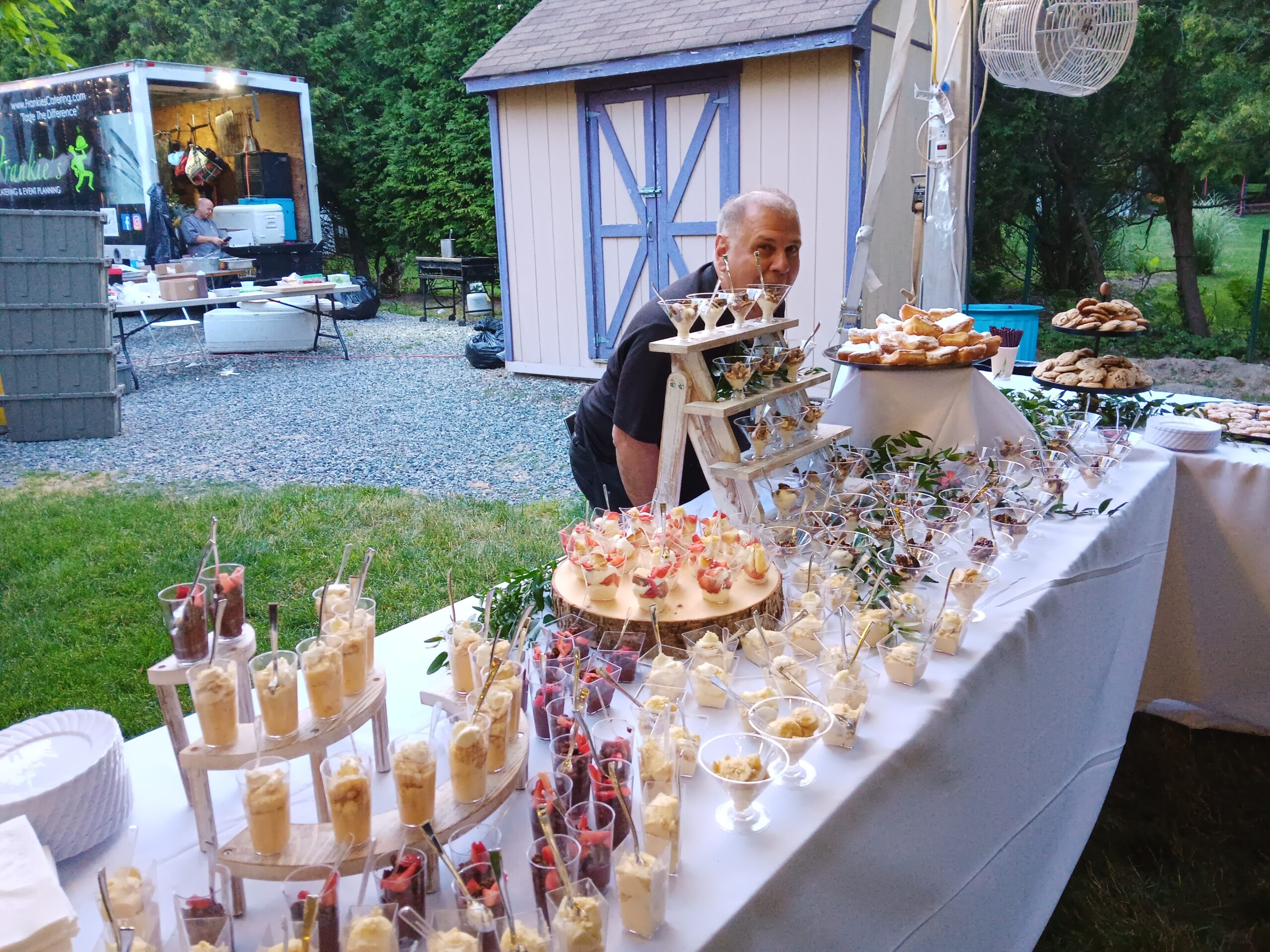 A person standing at a table with many different desserts.